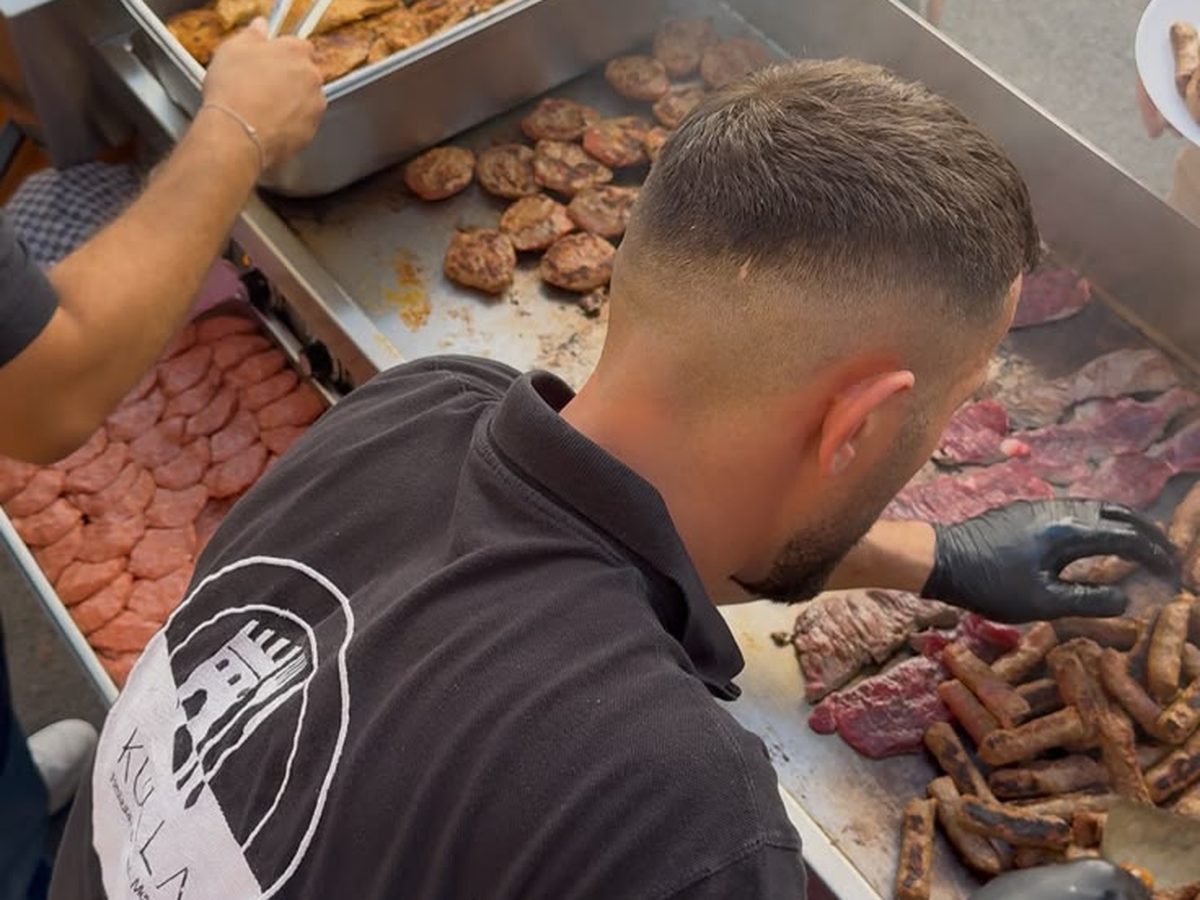Mitarbeitende stehen an der Grillstation eines Firmenfests an
