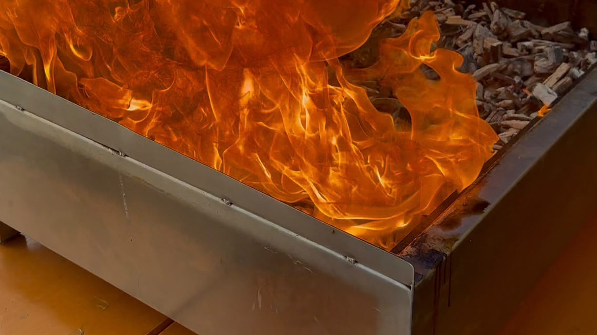Grillmeister grilliert Fleisch an einem Event, im Hintergrund Gäste und Buffet